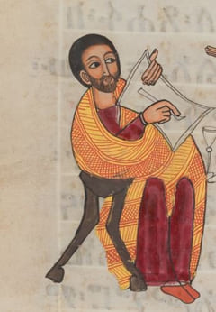 A seated scribe in a yellow-striped shamma over a crimson robe writes with a reed pen on a leaf held up before him, against a page of Ge'ez script.