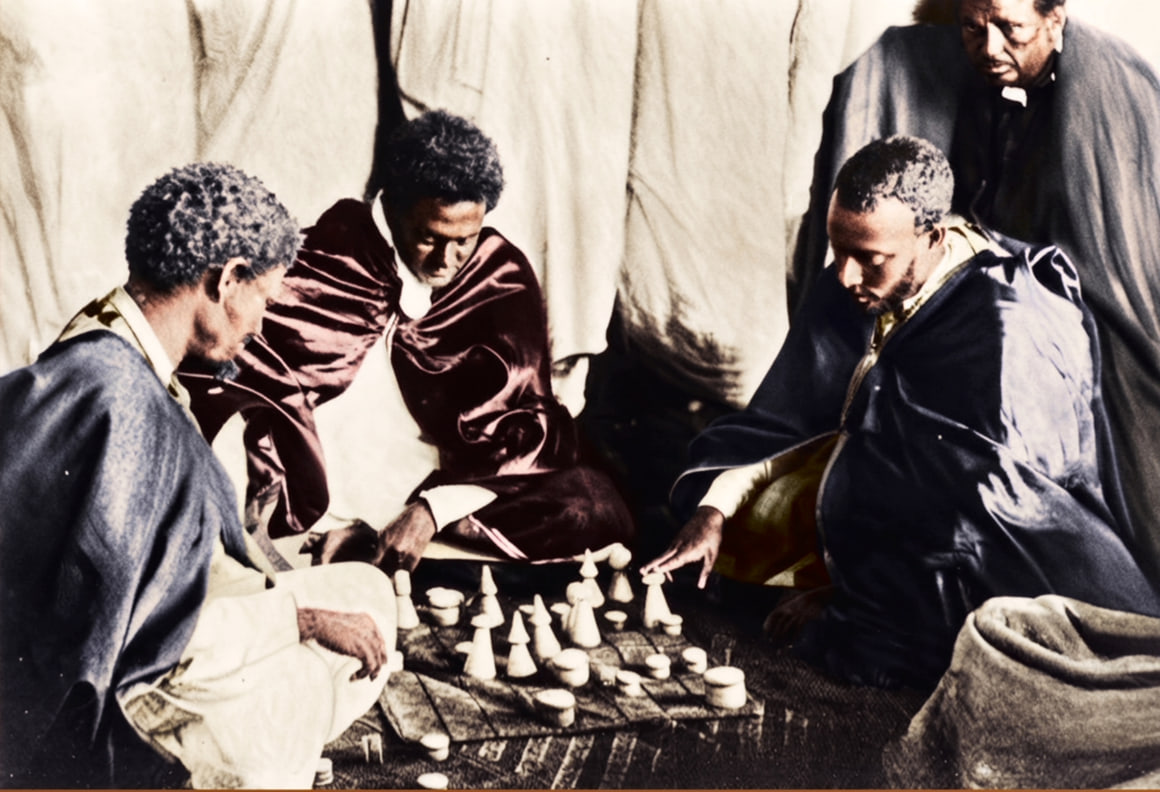 Four men seated on the ground around a ruled cloth board of turned playing pieces inside a tent, in an early twentieth-century photograph, colourised.