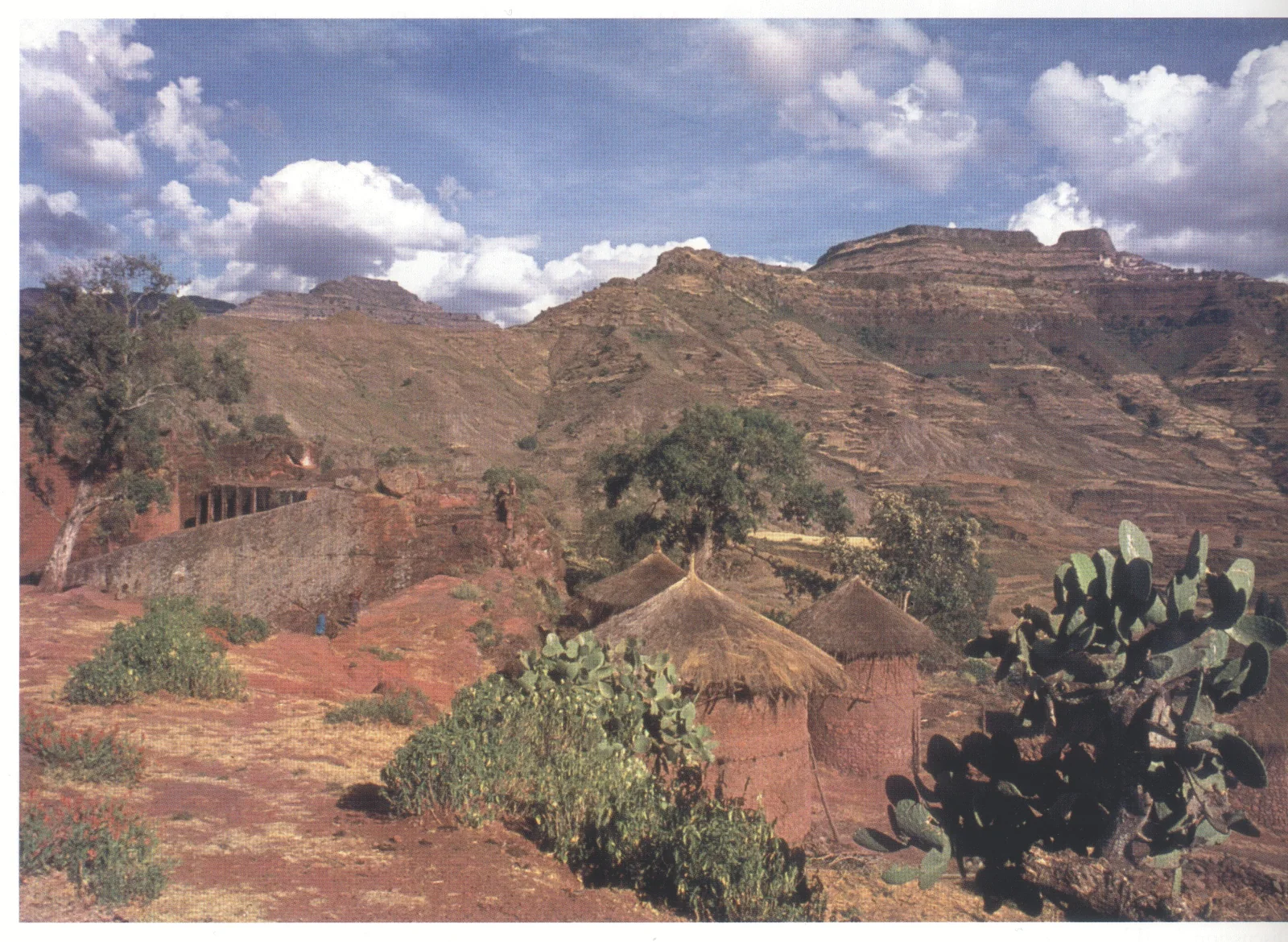 Lalibela, general view, looking east from near Beta Gabriel-Rafa’el — just visible at the left margin of the photograph — c. 1970. The cylindrical two-storey houses with conical thatched roofs were characteristic but are now rapidly disappearing. The peaks of Asheten form the horizon to the right.
