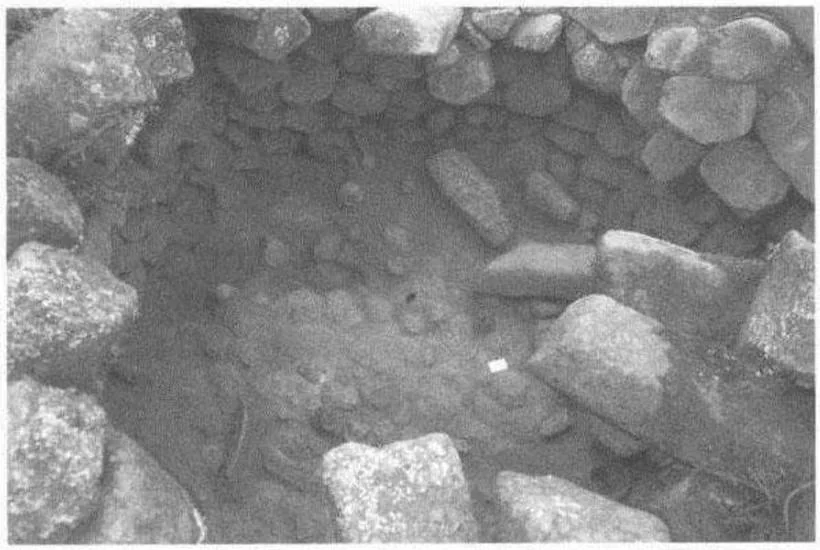 Fig. 3.7 - Tumulus 2 de Meshalà Maryam. Vue générale de la fouille de la chambre. Noter les prismes basaltiques à droite, restes de la couverture en encorbellement