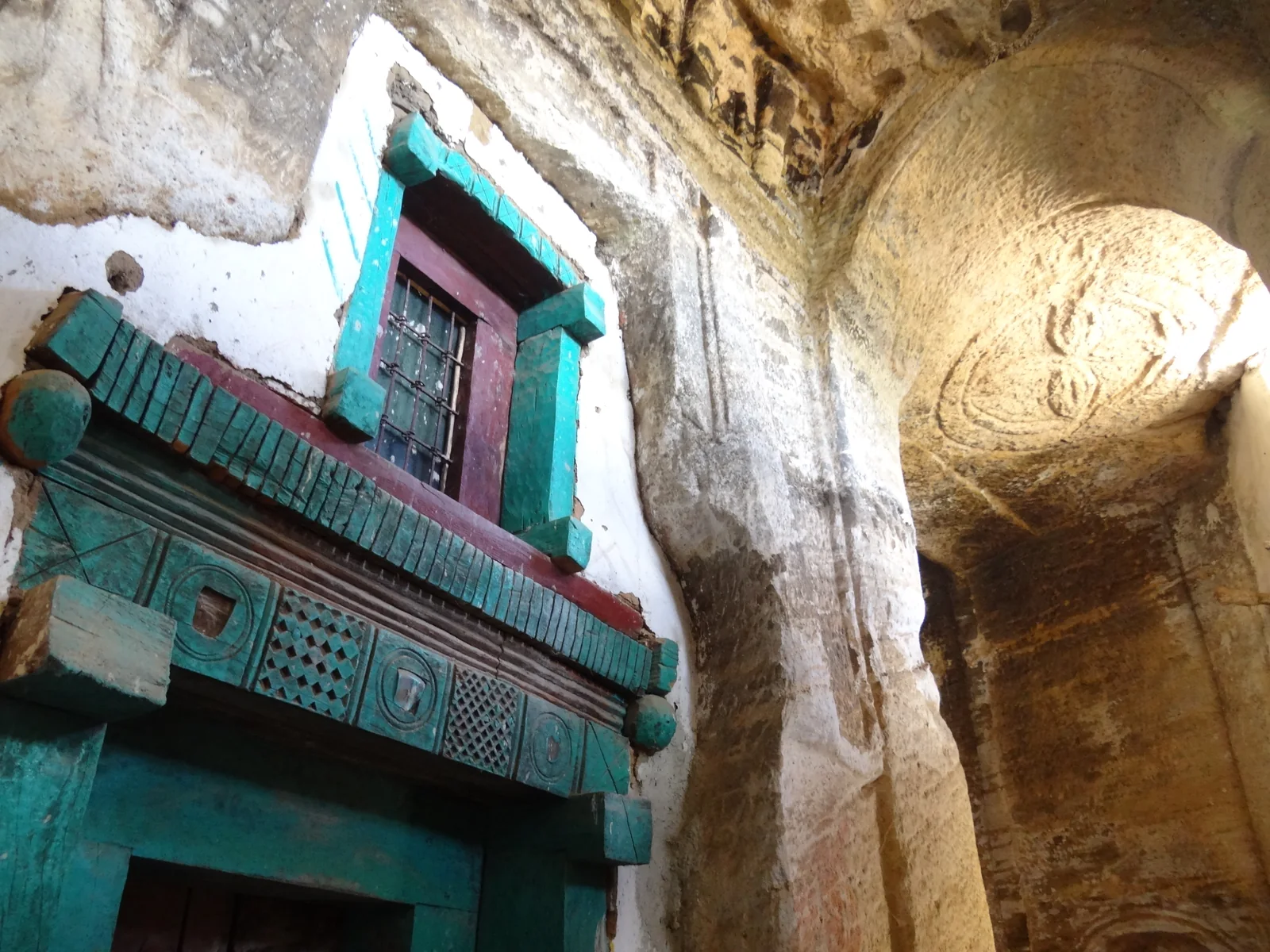 Madhane Alem Addi Qesho: oblique interior showing the timber doorway, rock-cut wall and barrel-vaulted bay.