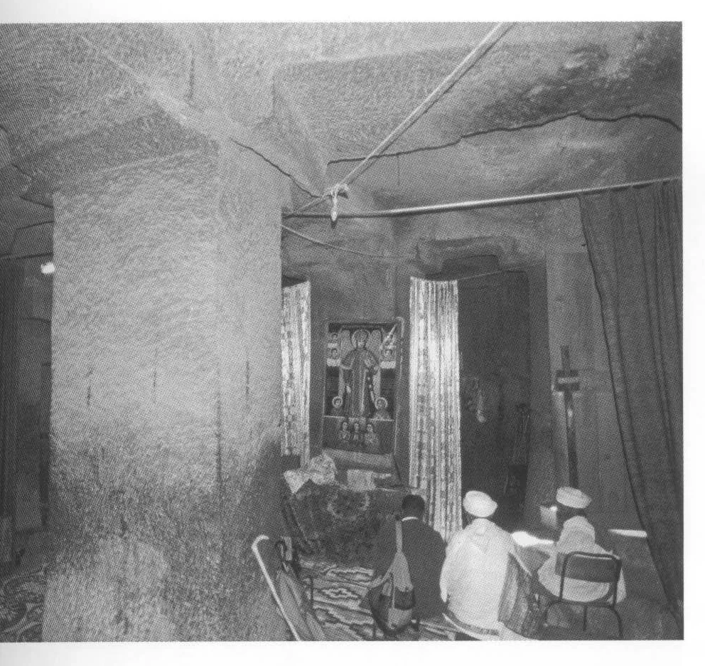 Beta Gabriel-Rafa’el, the interior of Beta Gabriel, from the southwest, 2006. Note the massive square pillar with angular brackets. The sanctuary is behind the curtains; the configuration of the entrance suggests that it was created at the same time as the ceiling was recut to form the brackets and architraves.
