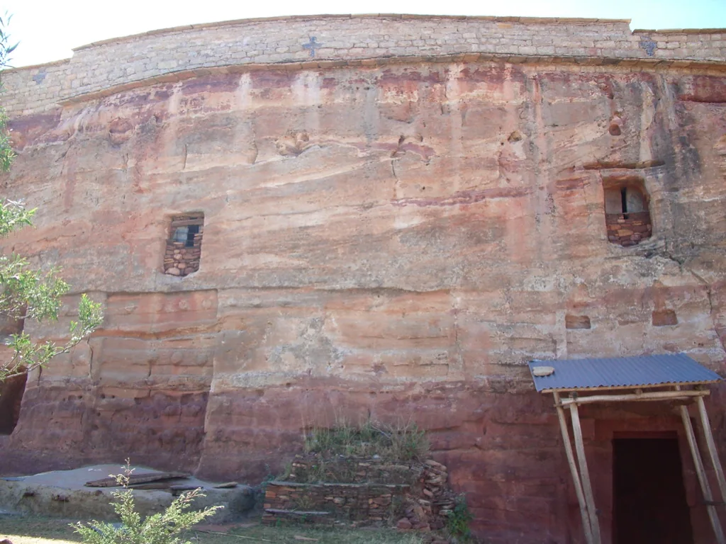 Maryam Debra Tsion: broad exterior of the excavated rock face, high wall, windows and lower doorway.